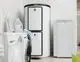 Vaillant Multifunktionsspeicher in Weiß, links stehend mit digitalem Display, neben einer weißen Waschmaschine und einer grünen Wäschebox im modernen Raum.